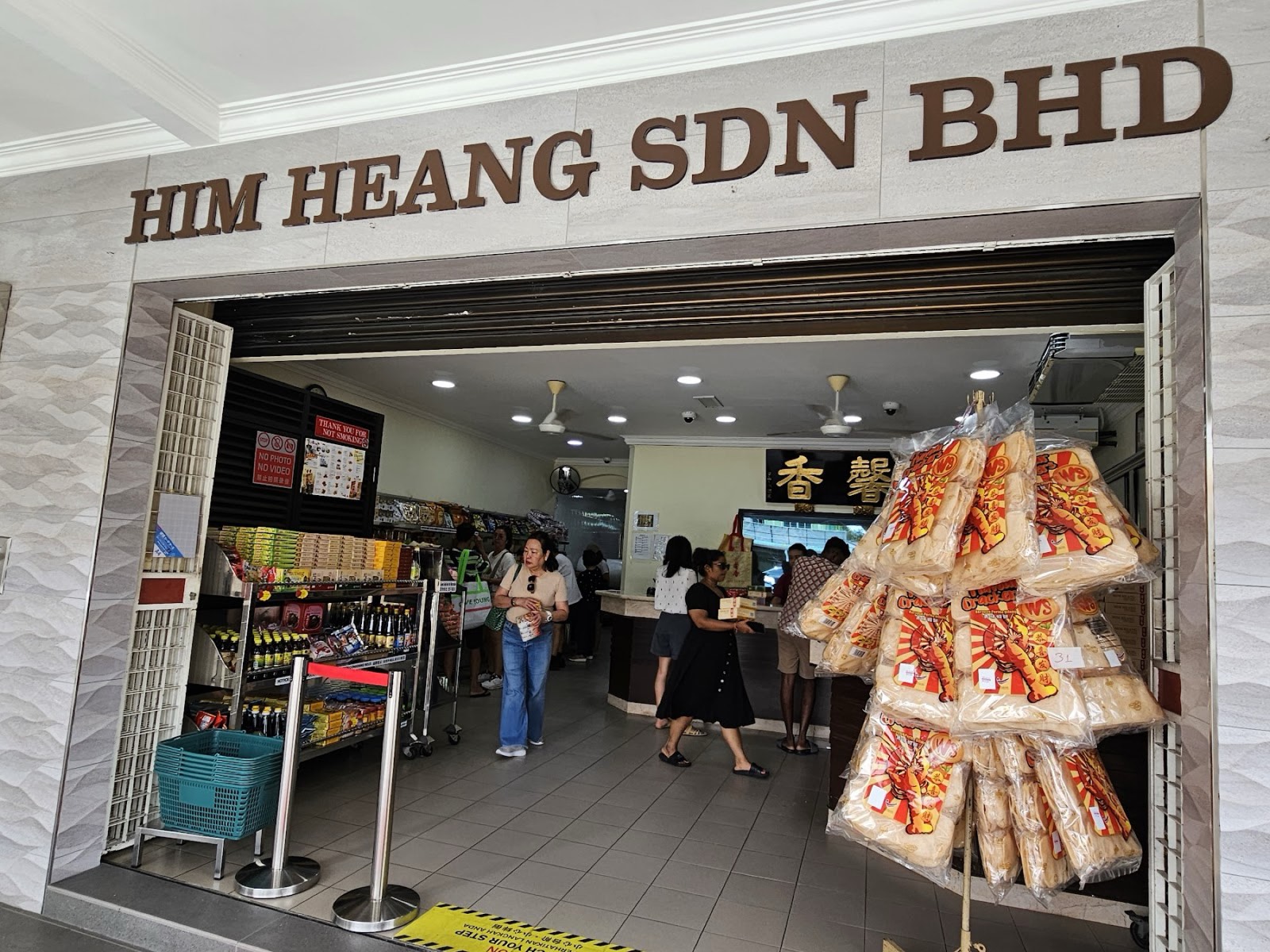 The Him Heang shop entrance with HIM HEANG SDN BHD signage and customers inside browsing the shelves