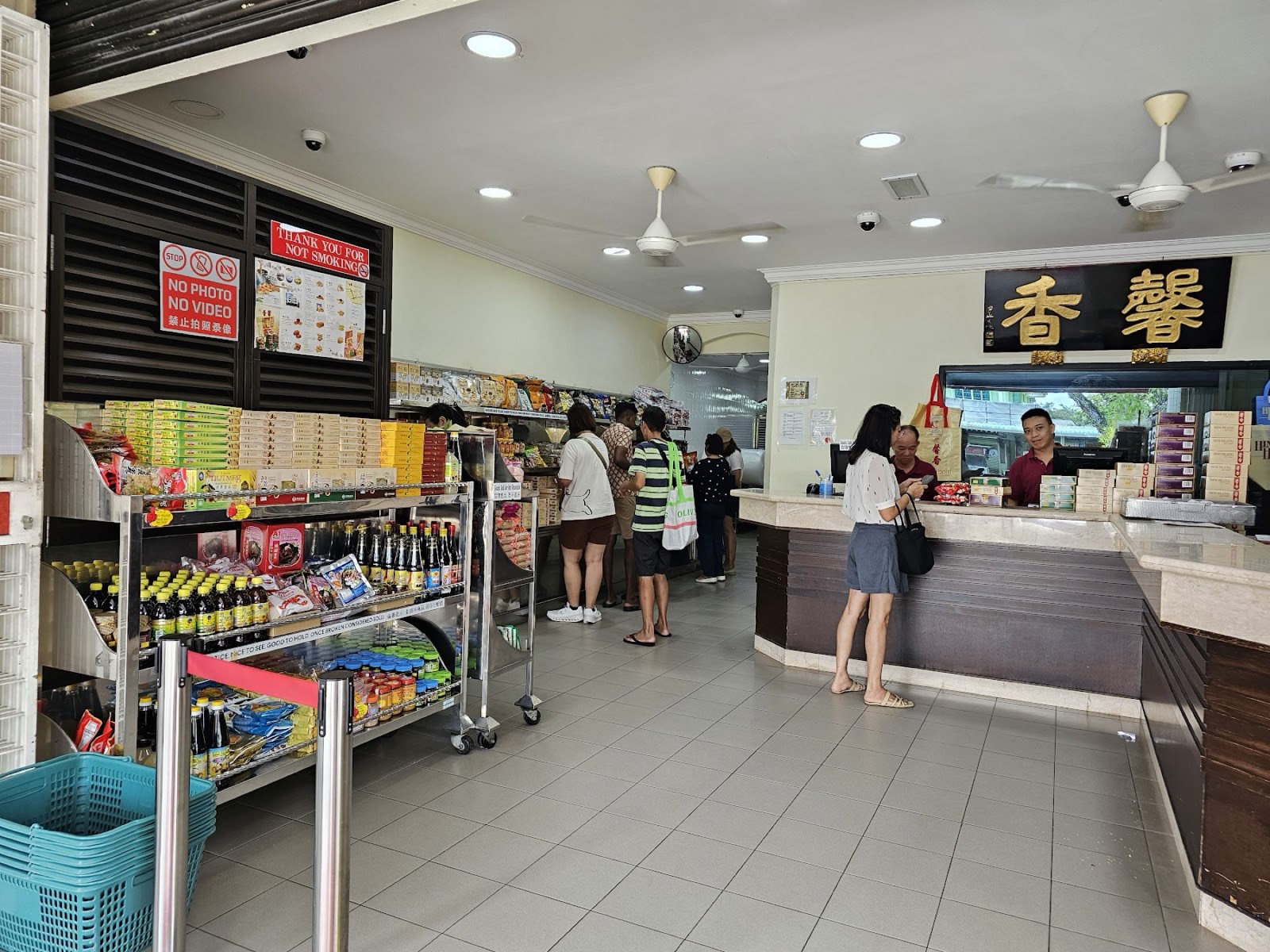 Inside Him Heang — customers at the marble counter beneath the gold 香馨 plaque and ceiling fans