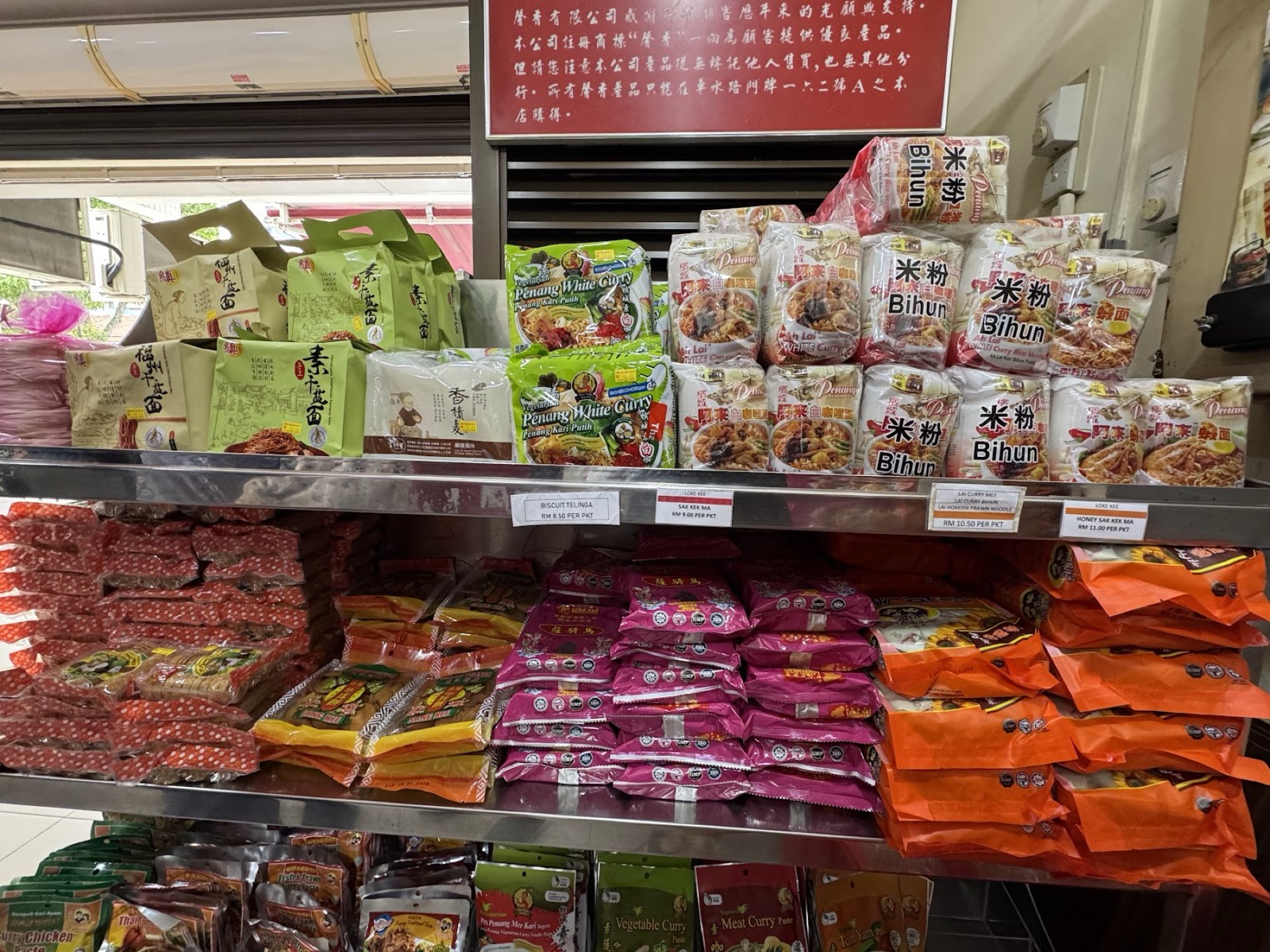 Shelves of packaged Penang keepsakes at Him Heang — nutmeg snacks, bihun and local treats