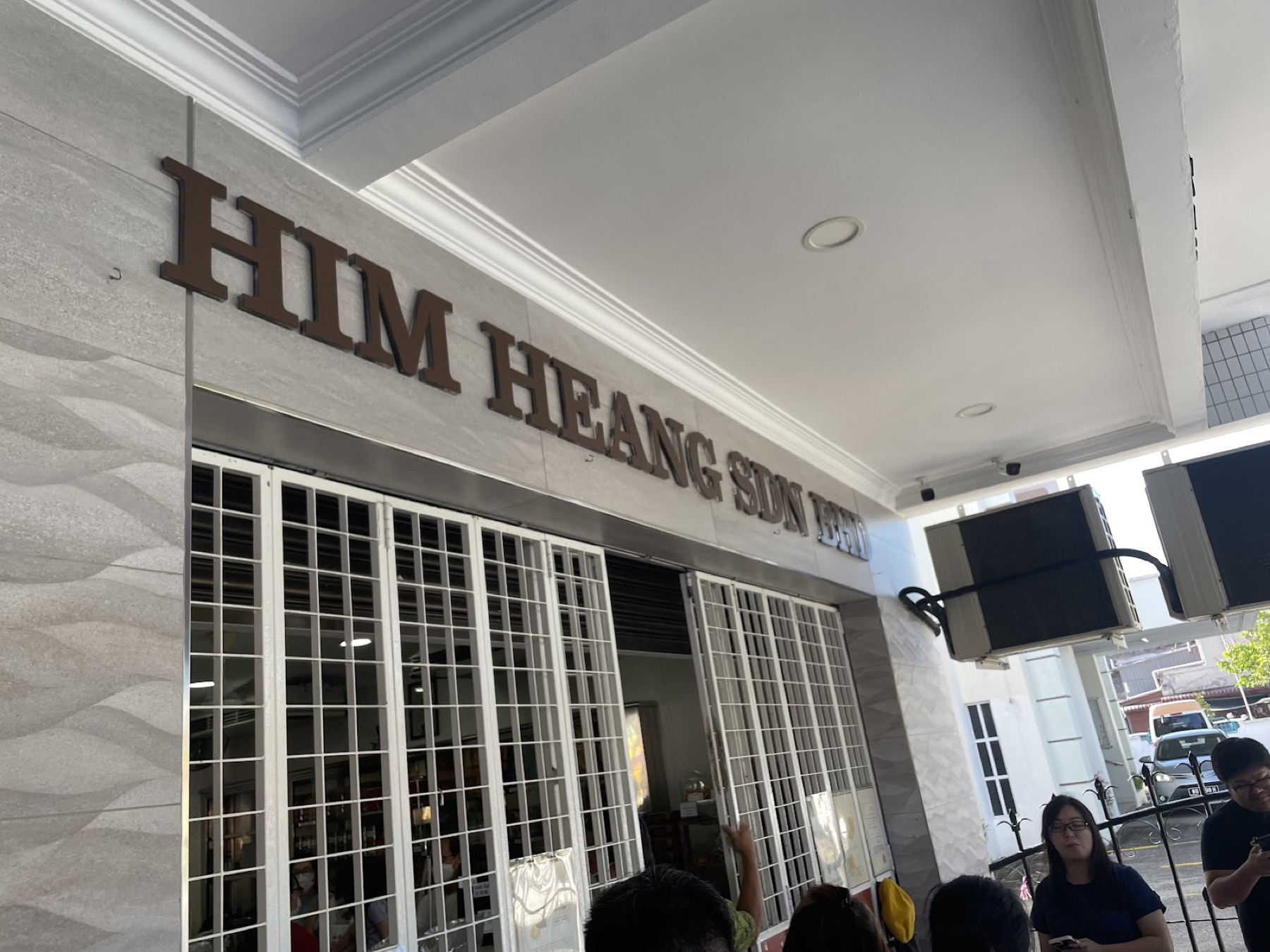 Close view of the HIM HEANG SDN BHD shopfront lettering in brown on the white stone facade