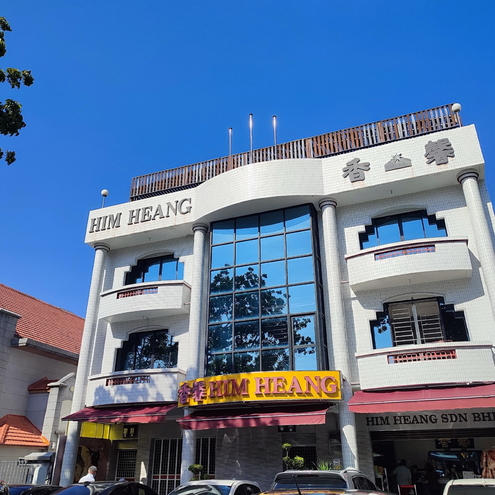 The Him Heang shopfront on Jalan Burma — a white building with the gold HIM HEANG sign and red awnings